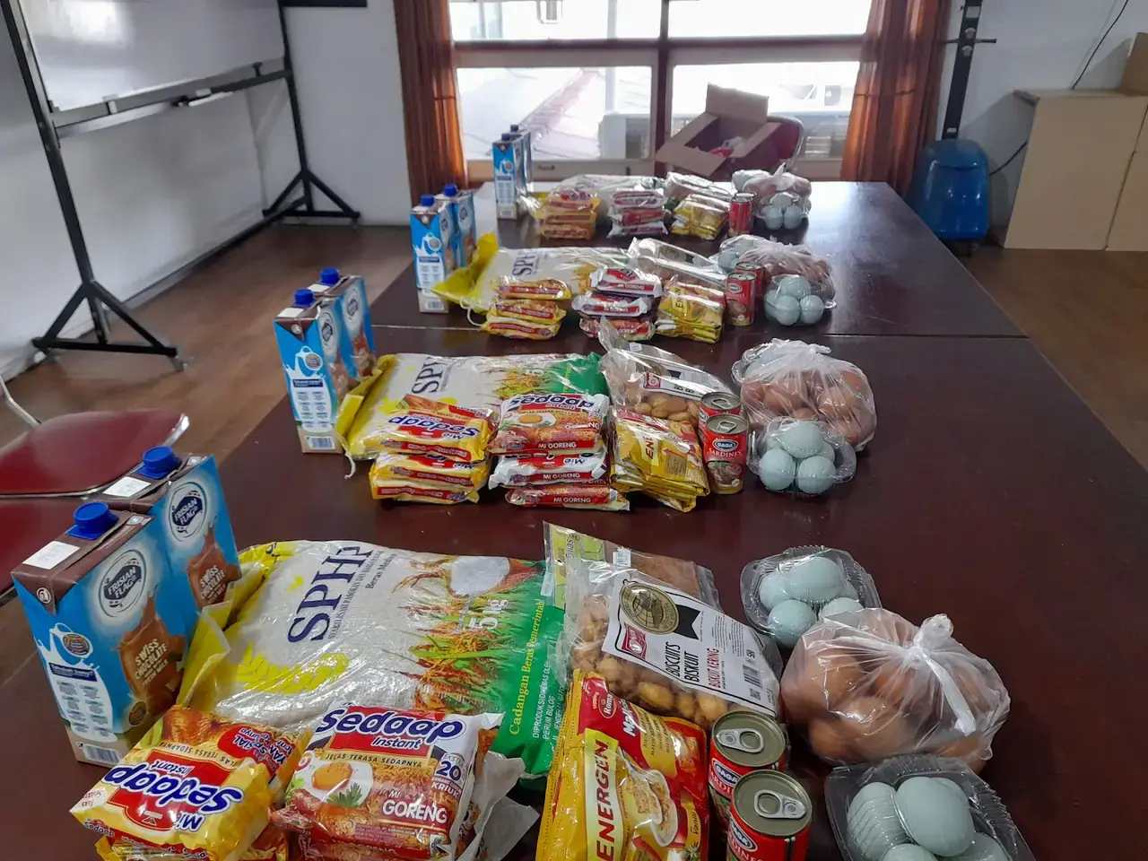 Paket tambahan gizi berisi susu, makanan, dan kebutuhan pokok tertata di atas meja